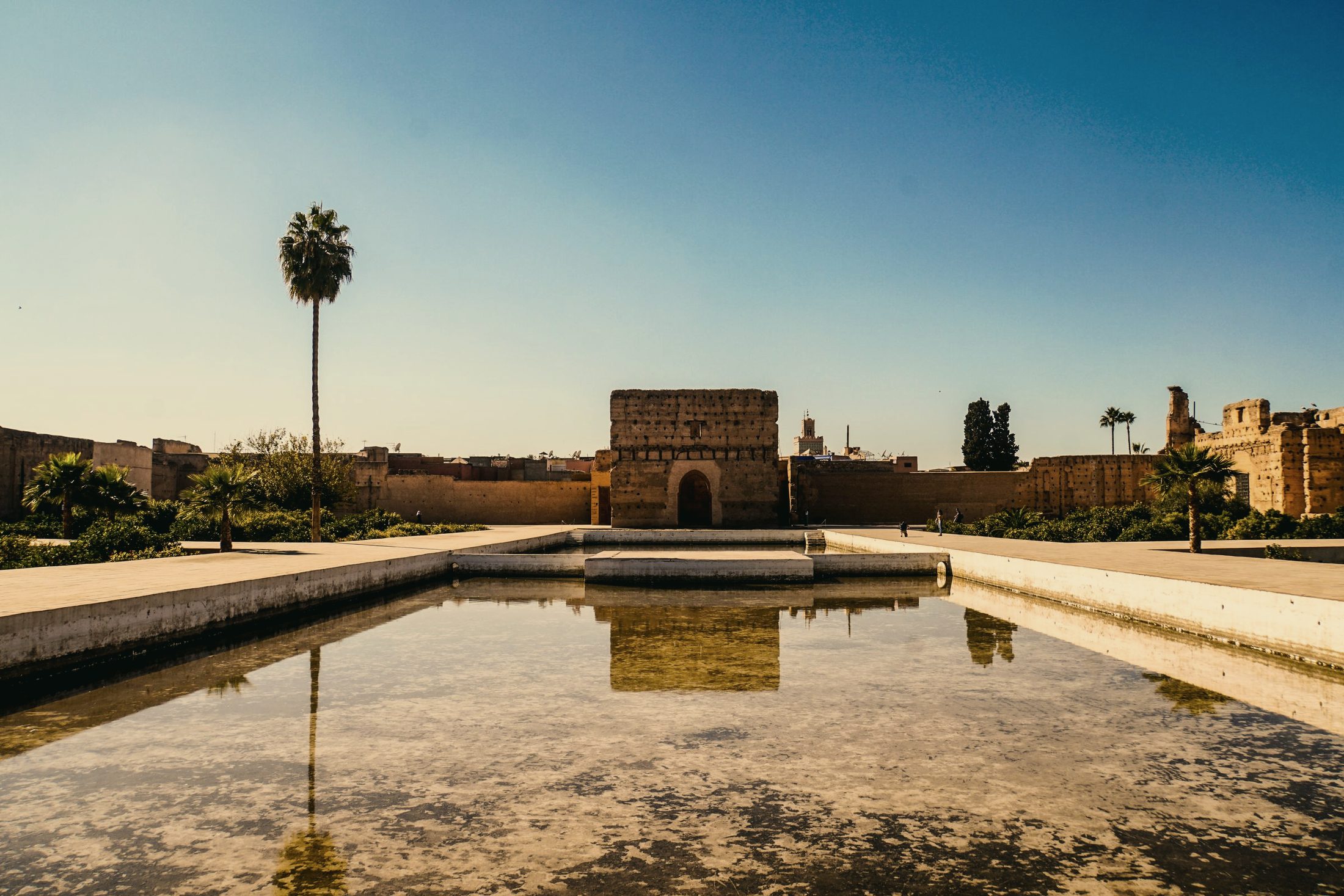 Le palais El Badi à Marrakech et son bassin de reflet, sous un ciel dégagé.